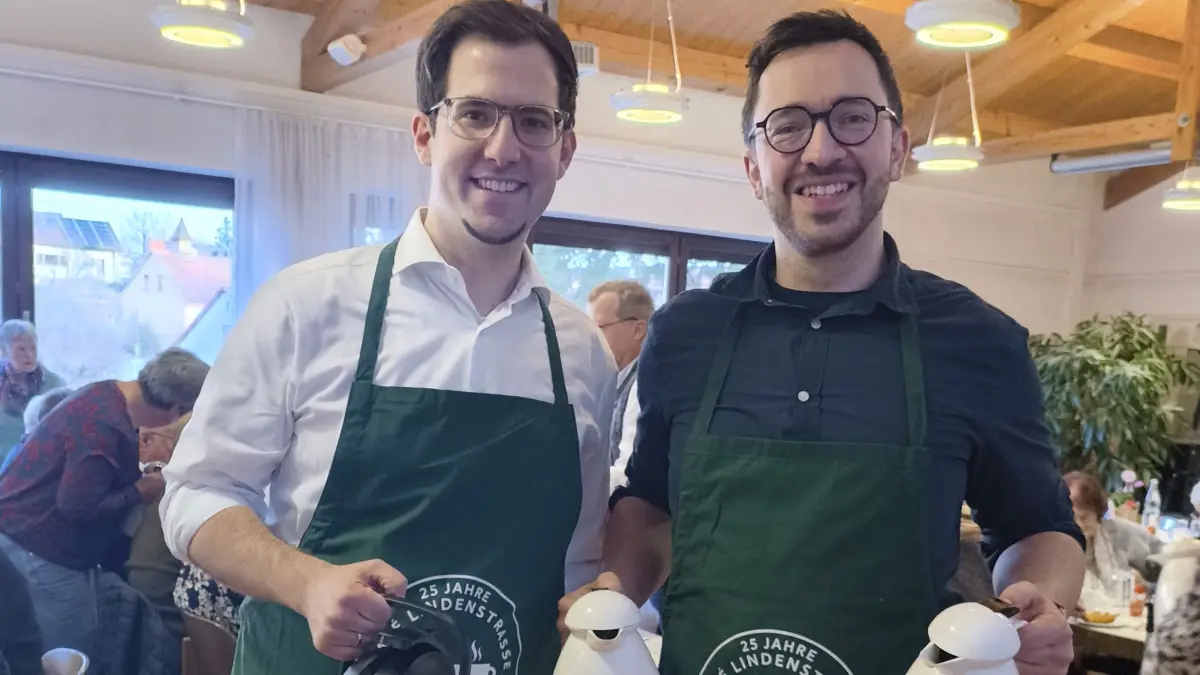 Sind das Brüder? Alter, Größe, Statur, Brille, Haarfarbe und am Samstag auch noch dieselben, grünen Schürzen mit "kreativ korrektem" Aufdruck zum Jubiläum des Cafés Lindenstraße. Schon vorher habe manch einer in Bodelshausen nach der möglichen Verwandtschaft gefragt, sagte Musiker Mathias Guischard bei der Feier launig. "Er ist zwei Jahre jünger als ich", sagte der 36-jährige Bürgermeister Florian King. Der vielen als CDU-Kandidat bei der letzten Bundestagswahl bekannte Christoph Naser (34) verpasste den Einzug ins Parlament knapp. Seit 100 Tagen ist er Pfarrer der Gemeinde. "Nein, wir sind nicht verwandt", stellte Naser klar. Beim Vorbereitungstreffen im Rathaus sei es flott gegangen, sagte Guischard. So wurde zum Beispiel das Logo für die Schürze kurzerhand mit ChatGPT erstellt. "Wenn die beiden loslegen, geht etwas voran", sagte Guischard. Daher sei er optimistisch für die nächsten Jahre und vielleicht seien sie ja "Brüder im Geiste".