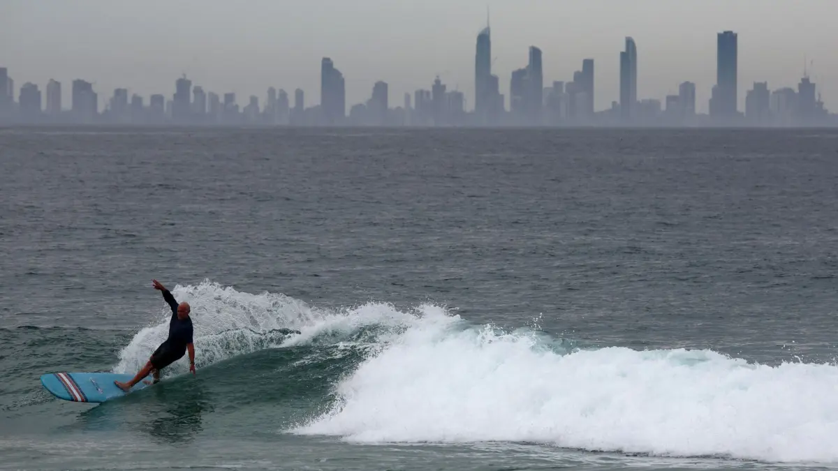 Wetter in Queensland: 23.12.2025, Australien, Coolangatta: Ein Surfer surft in Coolangatta an der Goldküste, wo über die Weihnachtszeit stürmisches Wetter vorhergesagt wird. Foto: Jason O'Brien/AAP/dpa +++ dpa-Bildfunk +++