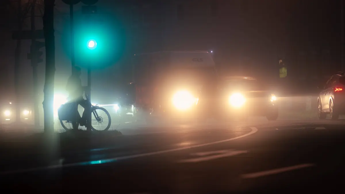 Verkehrssituation bei Dunkelheit: Verkehrssituation bei Dunkelheit Oldenburg, Deutschland, 20.12.2025: Ein Radfahrer steht bei grünem Ampellicht und Nebel im nächtlichen Straßenverkehr. *** Traffic situation in the dark Oldenburg, Germany, 20 12 2025 A cyclist stands in traffic at night with green traffic lights and fog