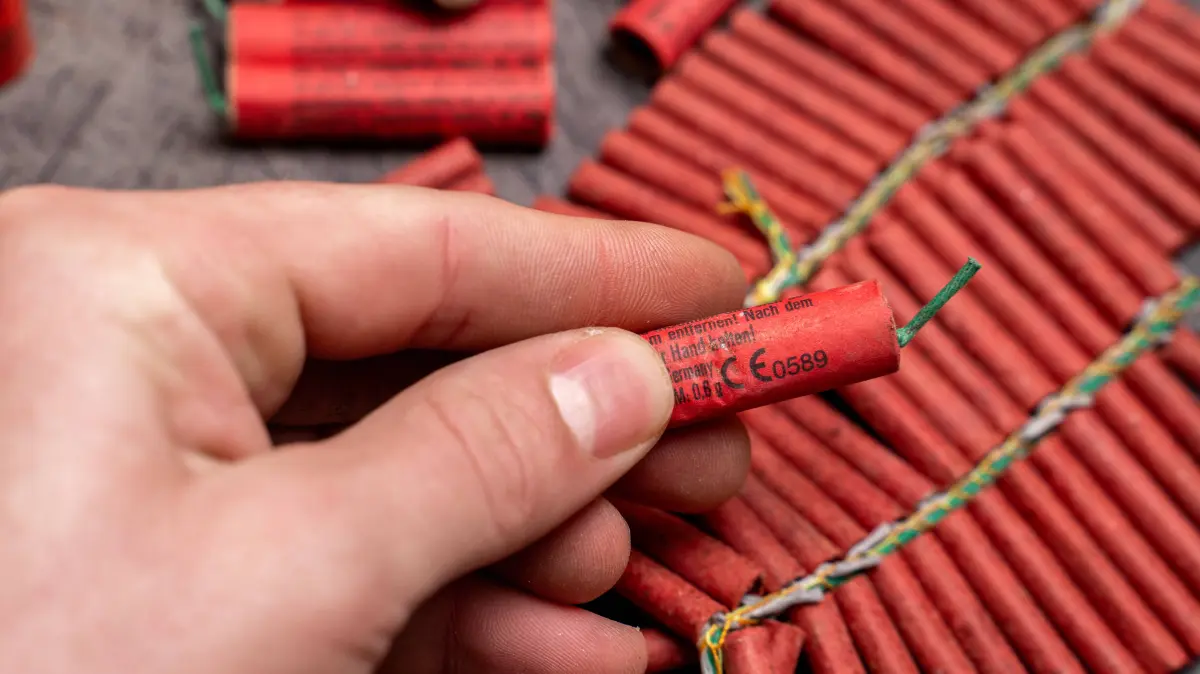 Bavaria, Germany - December 17, 2025: A hand holds a single firecracker in front of several fireworks. The close-up serv: Bavaria, Germany - December 17, 2025: A hand holds a single firecracker in front of several fireworks. The close-up serves as a symbolic image for pyrotechnics and highlights the risks, labeling, and dangers of handling firecrackers, especially around New Year s Eve. *** Eine Hand hält einen einzelnen Böller vor mehreren Feuerwerkskörpern. Die Nahaufnahme dient als Symbolbild für Pyrotechnik und verdeutlicht Risiken, Kennzeichnung und die Gefahren beim Umgang mit Böllern, besonders rund um Silvester.
