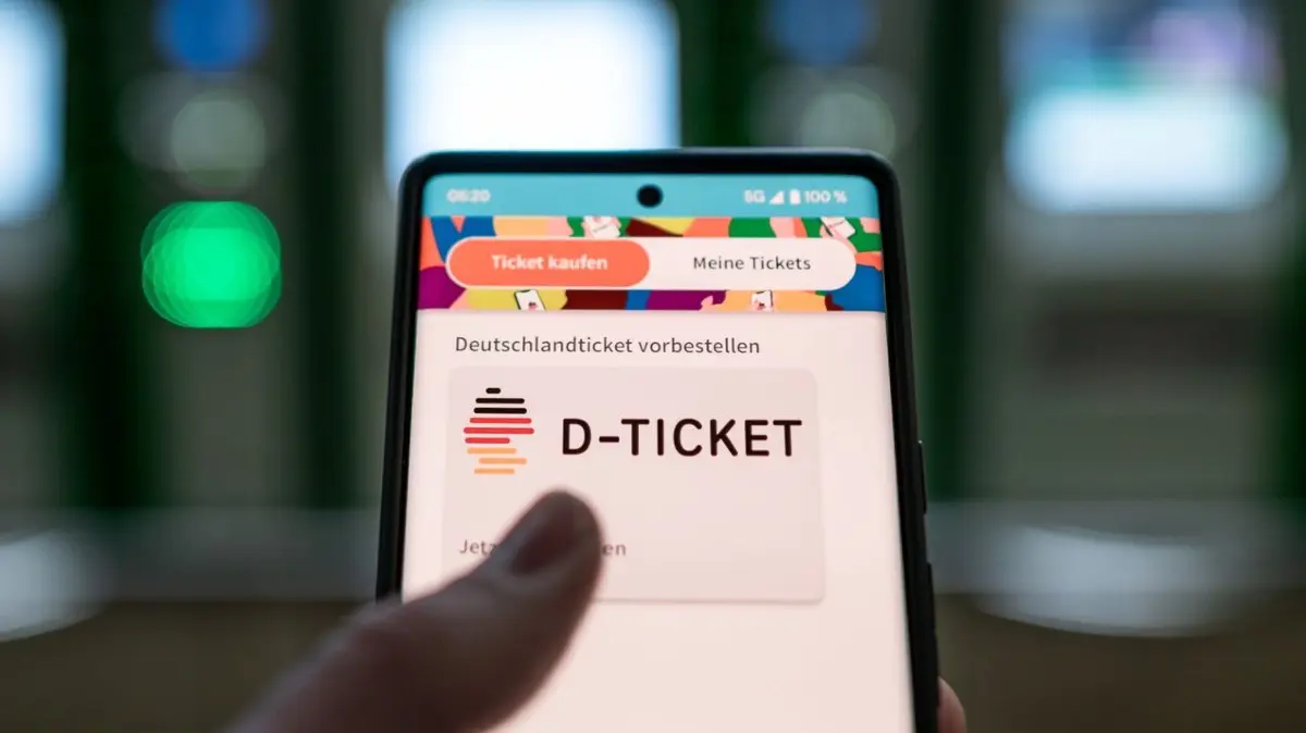 Deutschlandticket: ARCHIV - 03.04.2023, ---: Ein Mann hält ein Mobiltelefon, auf dem das «D-Ticket» gekauft werden kann, vor Ticketautomaten am Hauptbahnhof in der Hand. (zu dpa: «Viele Verkehrsverbünde erhöhen Fahrpreise zum 1. Januar») Foto: Fabian Strauch/dpa +++ dpa-Bildfunk +++