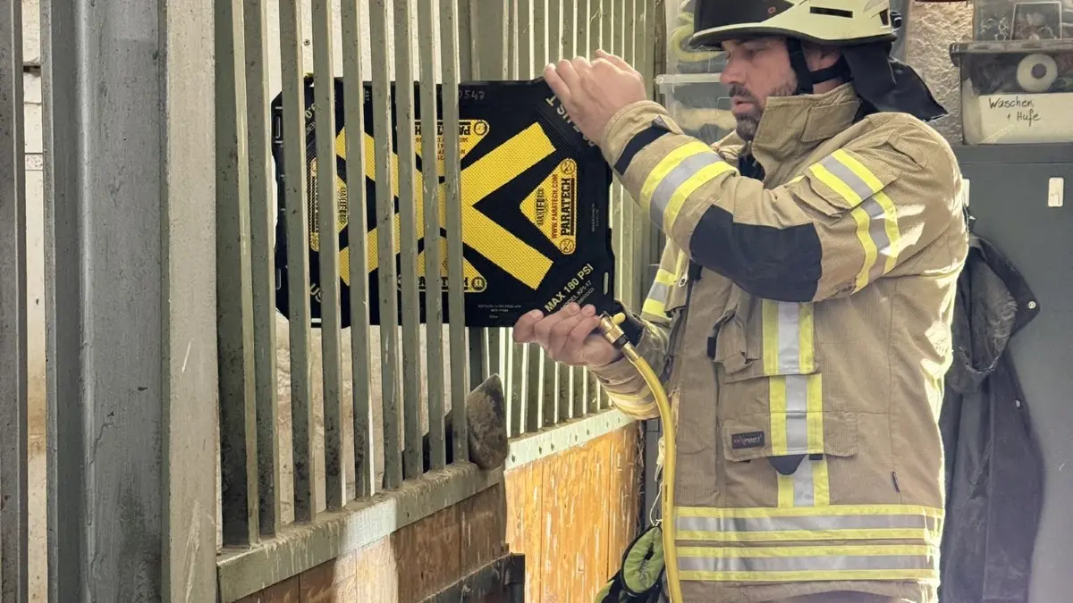 Michael Braitinger von der Feuerwehr Nersingen spreizt mit einem Hebekissen des Gitter der Pferdebox auf,