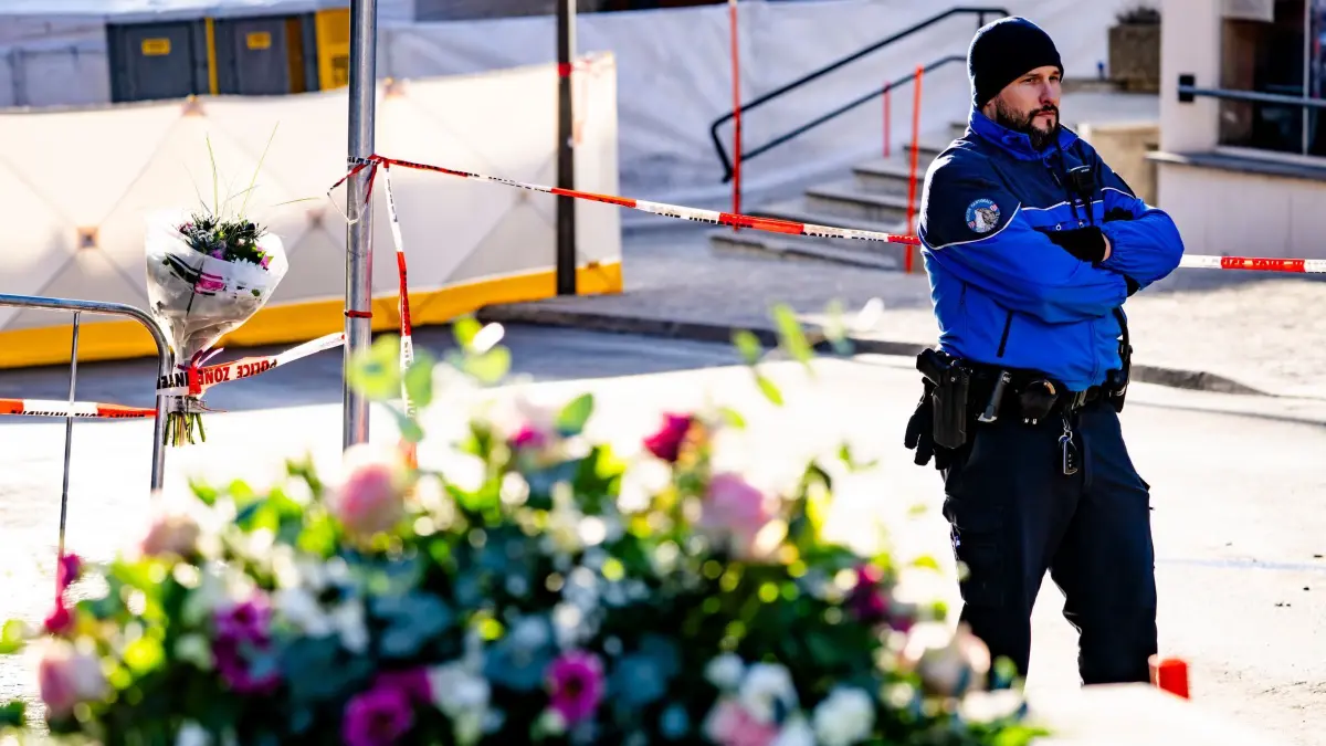 Tote bei Silvesterparty in Crans-Montana: 01.01.2026, Schweiz, Crans-Montana: Blumen sind zu sehen, während Polizeibeamte den Bereich inspizieren, in dem während der Silvesterfeierlichkeiten in der Bar und Lounge "Le Constellation" ein Feuer aus unbekannter Ursache ausbrach, bei dem es Tote und Verletzte gab. Foto: Jean-Christophe Bott/KEYSTONE/dpa +++ dpa-Bildfunk +++