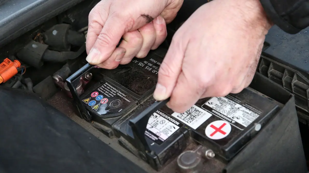 Mann wechselt eine Autobatterie: ILLUSTRATION - Gehört meist in die Hände von Fachleuten: Der Austausch der Autobatterie ist alles andere als einfach. (zu dpa: «Neue Autobatterie fällig: Das müssen Sie zum Tausch wissen») Foto: Bodo Marks/dpa-tmn - Honorarfrei nur für Bezieher des dpa-Themendienstes +++ dpa-Themendienst +++