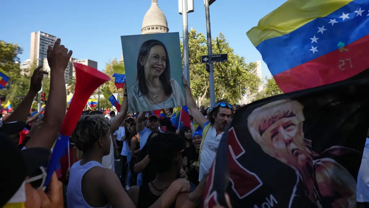 US-Angriffe auf Venezuela - Chile: 03.01.2026, Chile, Santiago: Venezolaner feiern mit einem Gemälde, das die Oppositionsführerin und Friedensnobelpreisträgerin Maria Corina Machado darstellt, nachdem US-Präsident Trump bekannt gegeben hatte, dass Venezuelas Präsident Maduro gefangen genommen und aus Venezuela ausgeflogen wurde. Foto: Esteban Felix/AP/dpa +++ dpa-Bildfunk +++