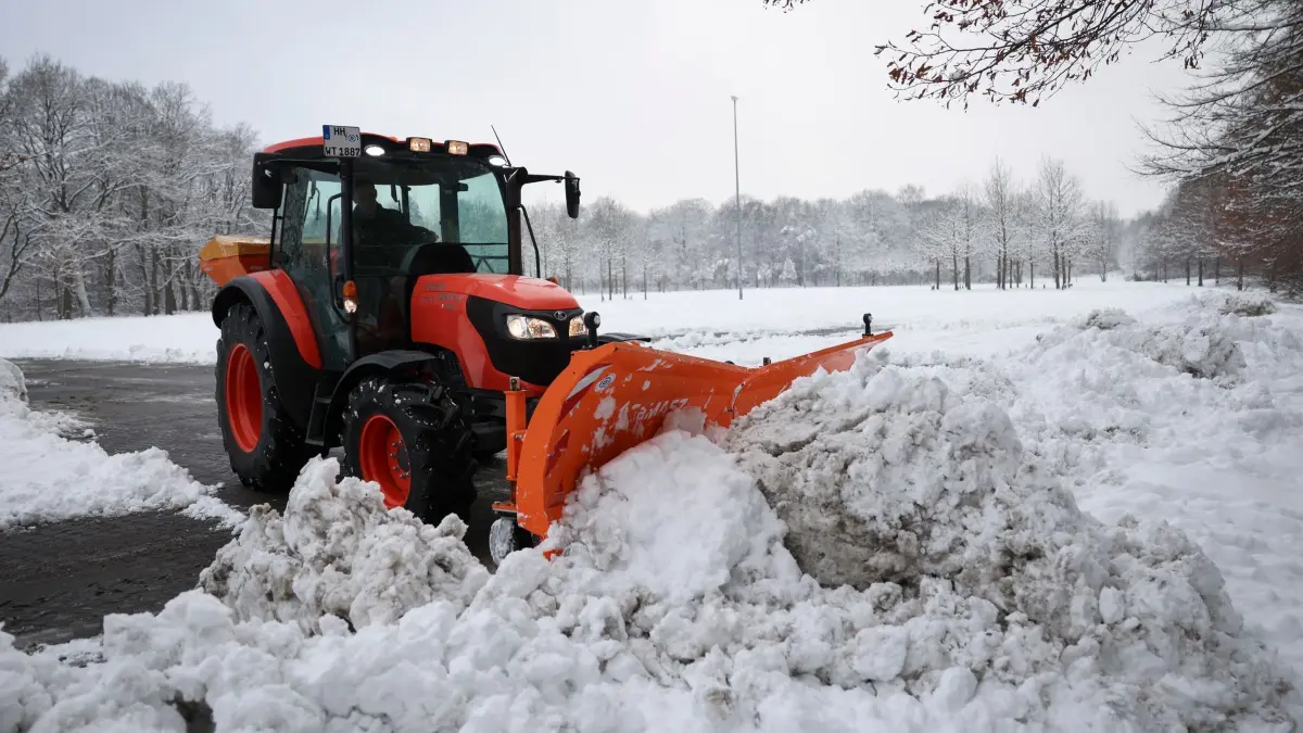 Winterwetter in Hamburg: 06.01.2026, Hamburg: Mit einem kleinen Traktor und Schneeräumschild befreit ein Mitarbeiter einen Teil des Parkplatz Rot am Volksparkstadion vom Schnee. Foto: Christian Charisius/dpa +++ dpa-Bildfunk +++