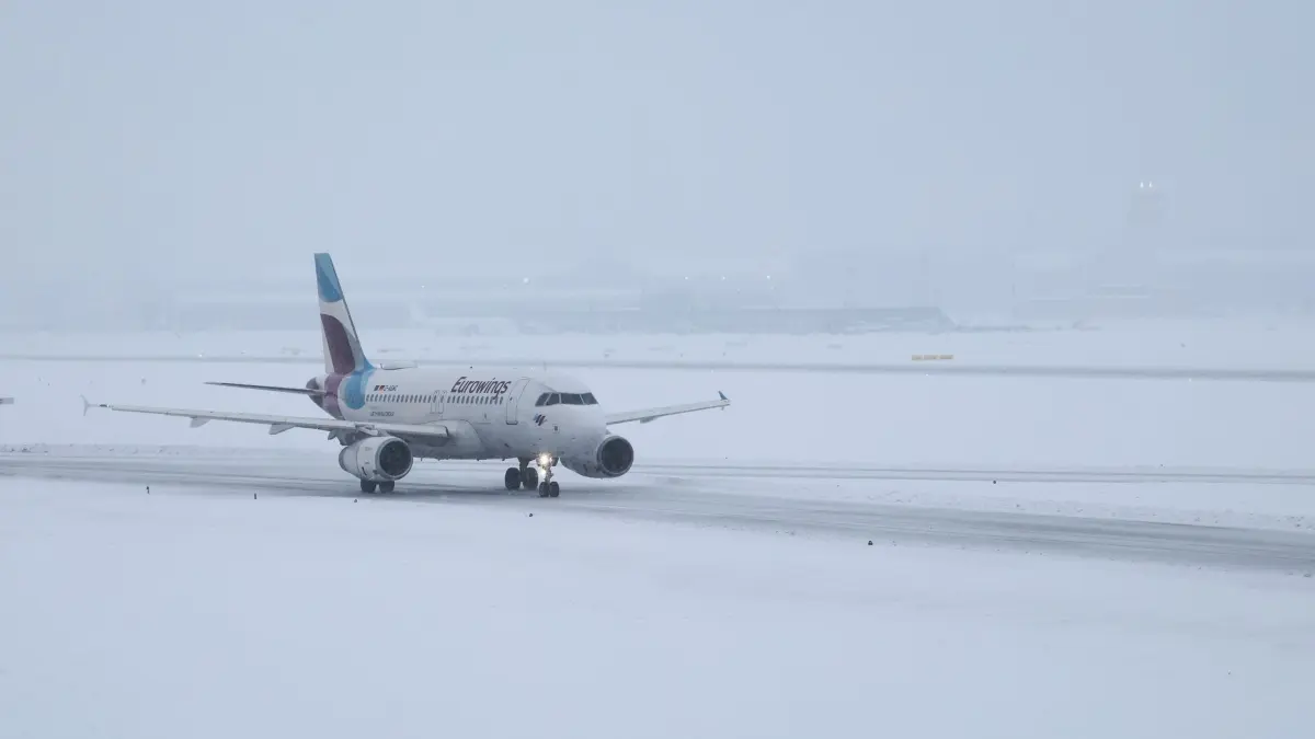 Winterwetter - Hamburg: 08.01.2026, Hamburg: Eine Maschine von Eurowings ist auf der verschneiten Runway auf dem Weg zur Start-und Landebahn am Flughafen Hamburg unterwegs. Foto: Christian Charisius/dpa +++ dpa-Bildfunk +++