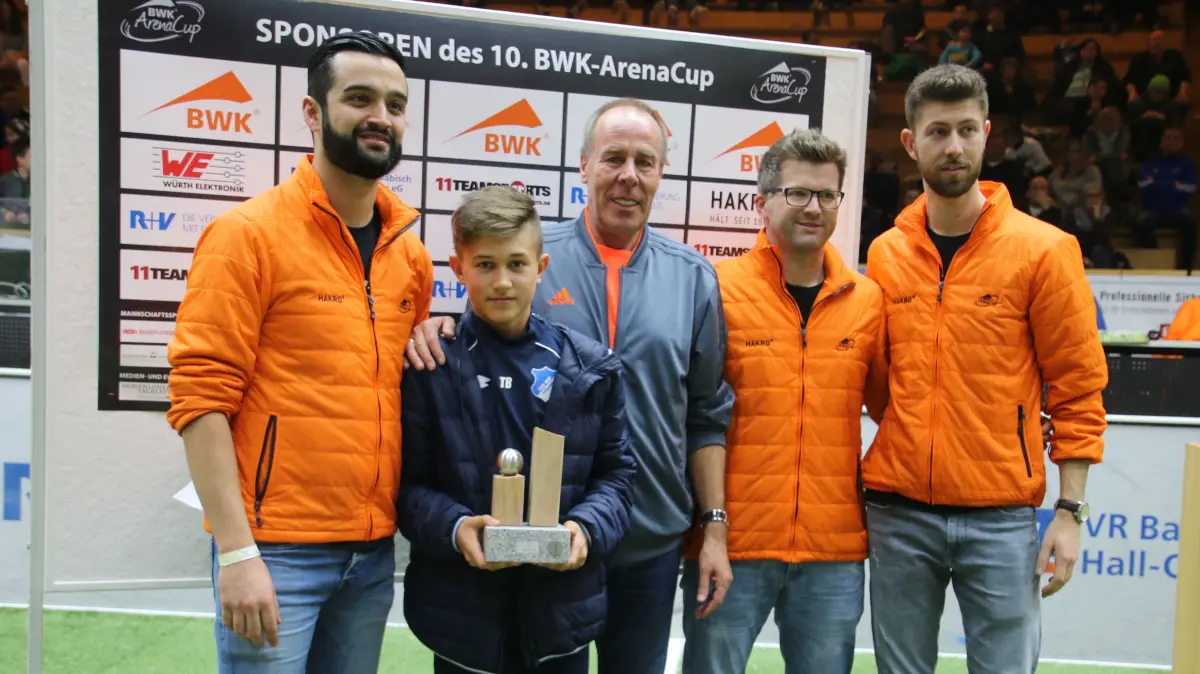 Tom Bischof wurde 2019 als bester Spieler des BWK-Arena-Cups ausgezeichnet. Er erhielt den Pokal, den er immer noch in seinem alten Kinderzimmer bei seinen Eltern stehen hat, von den Turnierorganisatoren Dario Caeiro (links), Jens Betsch (Zweiter von rechts) und Florian Bader (rechts) sowie von Namenssponsor Hartmut Layer.