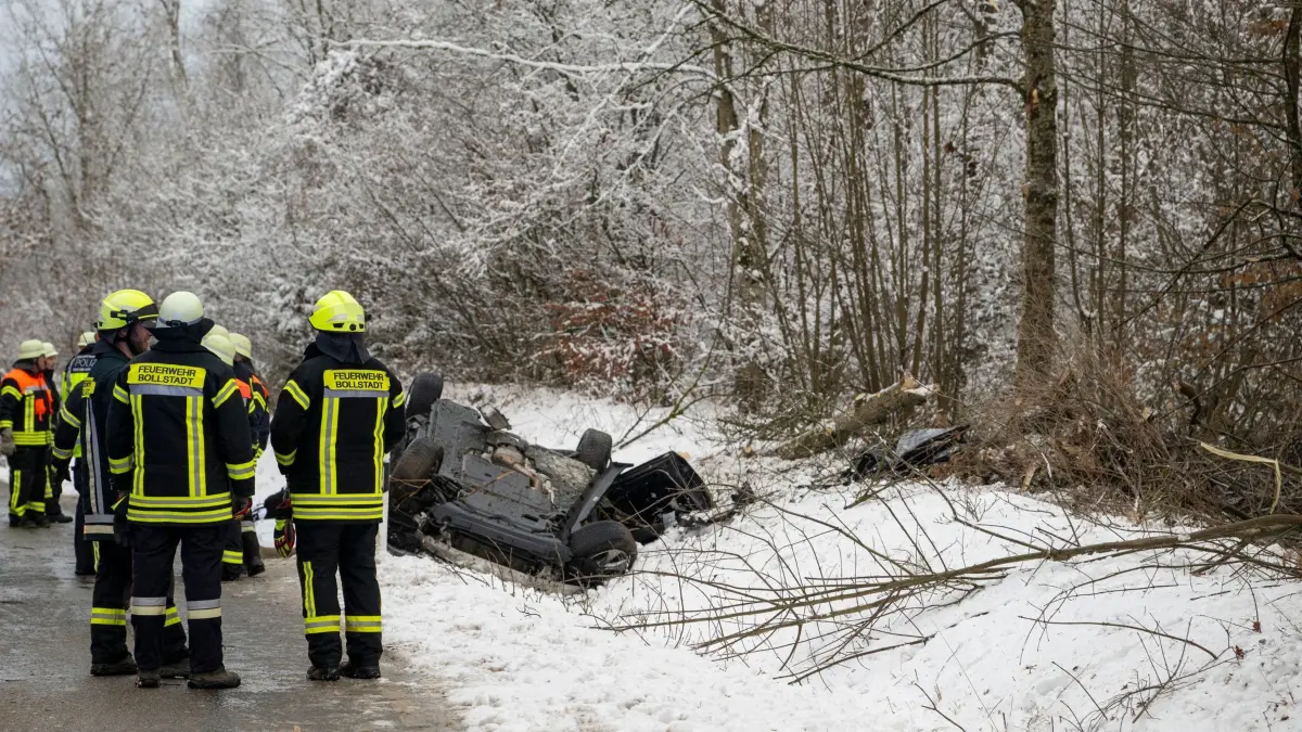 Tödlicher Unfall bei winterlichen Straßenverhältnissen: 10.01.2026, Baden-Württemberg, Dischingen: Feuerwehrleute stehen neben einem Auto, das auf dem Dach neben der Straße liegt. Bei winterlichen Straßenverhältnissen kam nahe dem Ortsteil Eglingen ein Mann mit seinem Auto von der Straße ab und prallte gegen einen Baum. Der Fahrer wurde dabei tödlich verletzt. Foto: Stefan Puchner/dpa +++ dpa-Bildfunk +++