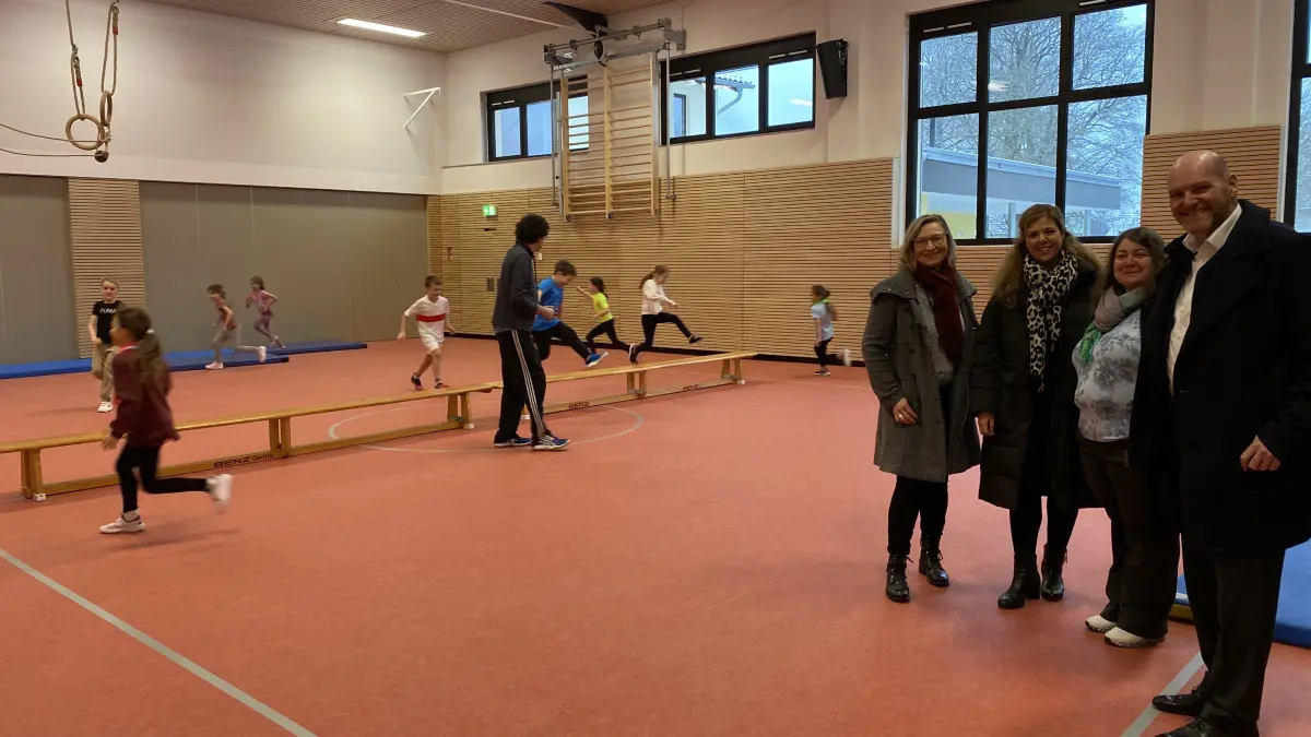 Nach mehr als zwei Jahren Sanierungsarbeiten kann die Halle in Ottendorf nach den Weihnachtsferien 2025/26 wieder in Betrieb genommen werden. Schulsport der Klasse 2a der Grundschule Ottendorf mit Lehrer Axel Horn. Auch auf dem Foto: Andrea Ingrisch (Leiterin Stadtentwicklung), Rektorin und Konrektorin Sandra Kübler und Oksana Shundriy-Diehm und Bürgermeister Stephen Brauer.
