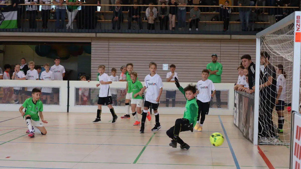 Eine Spielszene zwischen der SGM Sulzbach-Laufen/Frickenhofen/Gschwend (Weiß) gegen die „jungen Fohlen“ der Borussia aus Mönchengladbach. Staunende Kicker und Zuschauer fiebern mit, während der SGM-Keeper einen Gegentreffer verhindern möchte.