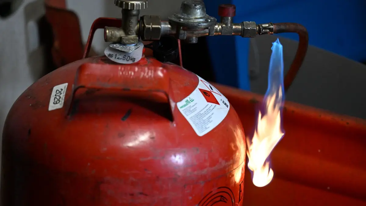 Gasflasche: ARCHIV - 07.08.2024, Nordrhein-Westfalen, Köln: Feuerwehrleute der Feuerwehr Köln demonstrieren wie schnell die Gasflasche eines Gasgrills wegen defekter Leitung Feuer fangen kann. (zu dpa: «Frau soll Explosion im Auto ihrer Chefin vorbereitet haben») Foto: Roberto Pfeil/dpa +++ dpa-Bildfunk +++