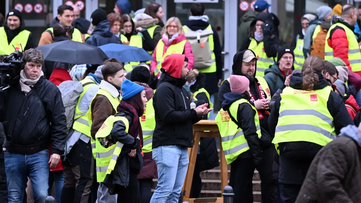Warnstreik an Uniklinik in Köln: 13.01.2026, Nordrhein-Westfalen, Köln: Beschäftigte der Uniklinik stehen bei einen Warnstreik vor dem Haupteingang. Mit den Warnstreiks möchte Verdi in den Tarifverhandlungen für den öffentlichen Dienst der Länder den Druck erhöhen. Foto: Federico Gambarini/dpa +++ dpa-Bildfunk +++