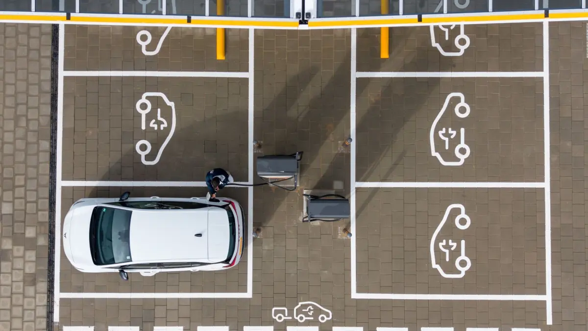 Neue E-Auto-Prämie soll rückwirkend ab Jahreswechsel gelten: ARCHIV - 22.10.2025, Sachsen, Klipphausen: Ein Mann steht auf einem Ladepark der EnBW Energie Baden-Württemberg AG und steckt ein Ladekabel in den Tankstutzen eines Elektroautos (Aufnahme mit einer Drohne). Bestimmte Autokäufer in Deutschland können für in diesem Jahr neu zugelassene E-Autos auf eine neue Kaufprämie der Bundesregierung bauen. (zu dpa: «Neue E-Auto-Prämie soll rückwirkend ab Jahreswechsel gelten») Foto: Sebastian Kahnert/dpa +++ dpa-Bildfunk +++