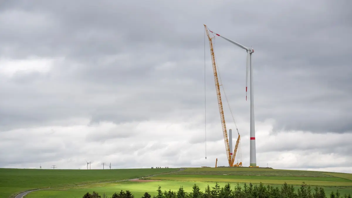 Neue Windkraftanlagen in der Eifel: ARCHIV - 05.06.2024, Rheinland-Pfalz, Obergeckler: Während dichte, dunkle Wolken am Himmel ziehen, werden im Windpark Obergeckler riesige Windkraftanlagen errichtet. (zu dpa: «Mittelfeldplatz beim Windenergie-Ausbau - viel genehmigt») Foto: Harald Tittel/dpa +++ dpa-Bildfunk +++