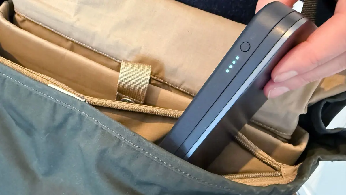 Mann steckt eine Powerbank in seinen Rucksack: ILLUSTRATION - Nur noch im Handgepäck und mit maximaler Kapazität von 100 Wattstunden: Lufthansa begrenzt die Nutzung und Mitnahme von Powerbanks in Flugzeugen. (zu dpa: «Powerbanks im Flugzeug: Lufthansa verschärft die Regeln») Foto: Till Simon Nagel/dpa-tmn - Honorarfrei nur für Bezieher des dpa-Themendienstes +++ dpa-Themendienst +++