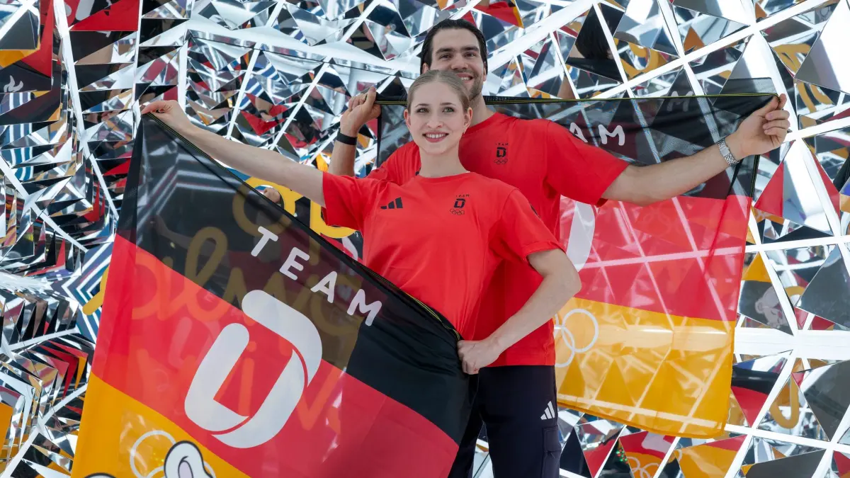 Olympia Einkleidung Sportler: 19.01.2026, Bayern, München: Die Eiskunstläufer Minerva Fabienne Hase und Nikita Wolodin stehen während der Einkleidung für die Winterspiele in Mailand in einer Photobox für ein Foto zusammen. Foto: Peter Kneffel/dpa +++ dpa-Bildfunk +++