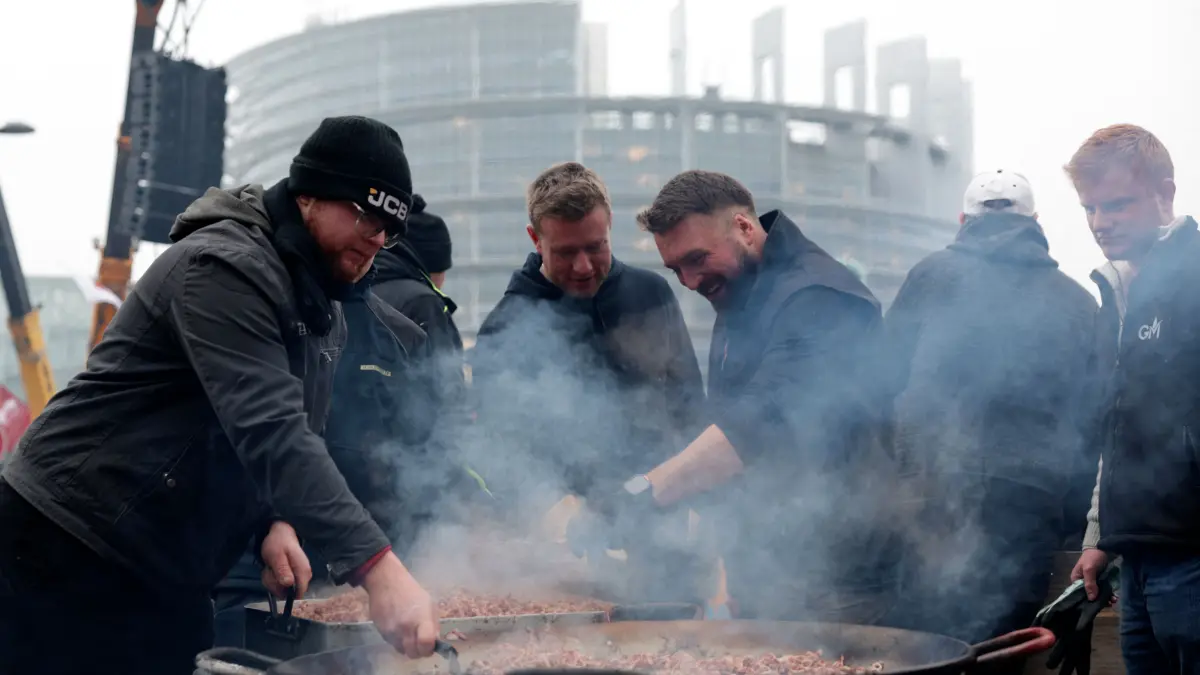 Farmers cook during a protest by European farmers against the free trade agreement between the European Union and the Mercosur countries, ahead a vote on a referral to the courts, in front of the European Parliament in Strasbourg on January 21, 2026. Called by the FNSEA, France's leading national agricultural union, some 4,000 farmers from across the European Union, including Italy, Belgium, and Germany, are expected to attend the protest. MEPs will not vote on the entire agreement with Mercosur until the coming months, but they are set to vote on Wednesday on whether to refer the matter to the Court of Justice of the European Union (CJEU). (Photo by Romeo BOETZLE / AFP)