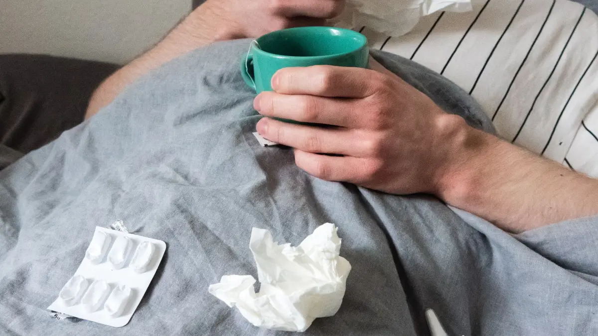 Grippe: ARCHIV - 12.12.2023, Niedersachsen, Hannover: Ein Mann liegt mit Taschentüchern, Teetasse, Nasenspray und Tabletten im Bett (gestellte Szene). (zu dpa: «Grippefälle im Norden - Hausärzte: «Saison in vollem Gange»») Foto: Philip Dulian/dpa +++ dpa-Bildfunk +++