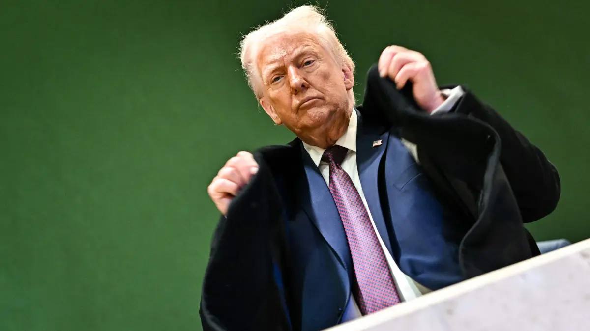 US President Donald Trump adjusts his jacket as he leaves the Congress Centre during the World Economic Forum (WEF) annual meeting in Davos on January 22, 2026. US President Donald Trump will show off his new "Board of Peace" at Davos on January 22, 2026 burnishing his claim to be a peacemaker a day after backing off his own threats against Greenland. Originally meant to oversee the rebuilding of Gaza after the war between Hamas and Israel, the board's charter does not limit its role to the Strip, and has sparked concerns that Trump wants it to rival the United Nations. (Photo by Fabrice COFFRINI / AFP)