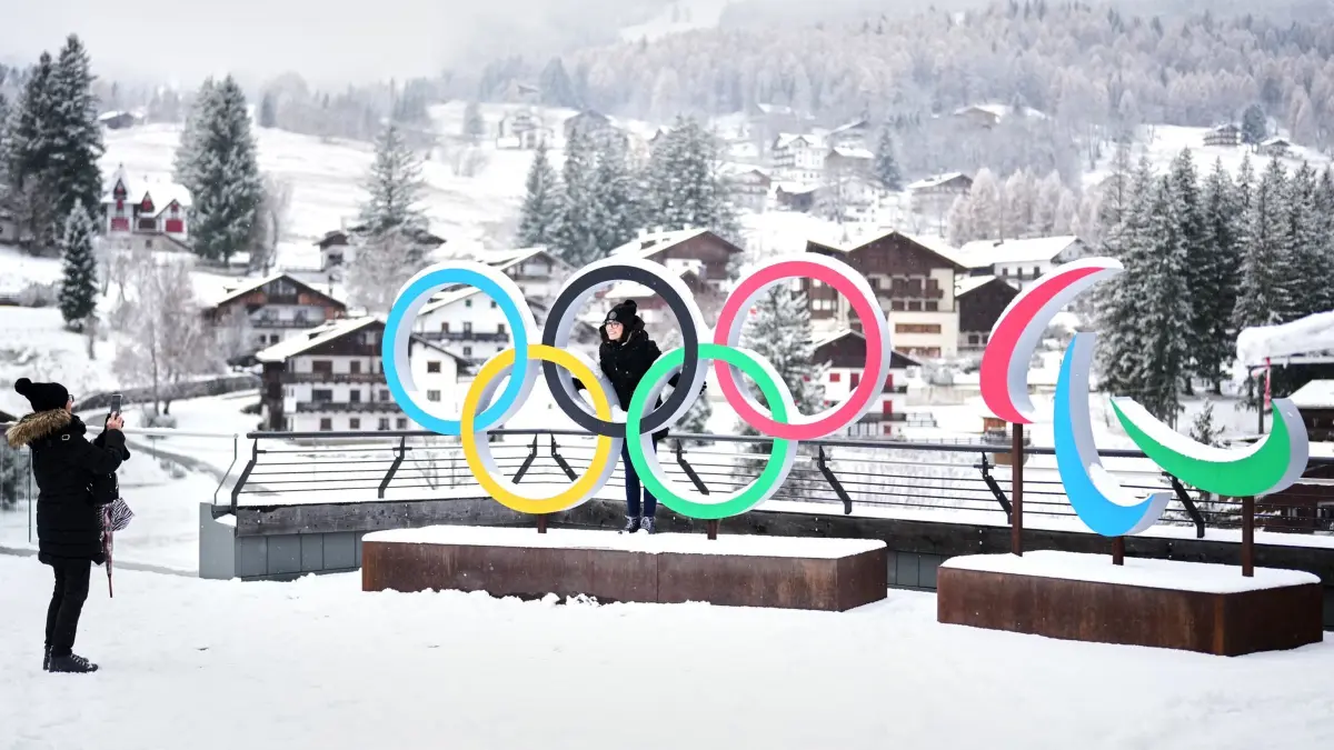 Vor den Olympischen Winterspielen in Italien: ARCHIV - 20.11.2025, Italien, Cortina D'Ampezzo: Menschen machen Fotos vor den Ringen der Olympischen Winterspiele und Paralympics in Cortina D'Ampezzo. (zu dpa: «Olympia-Karten für 9.000 Euro: Italien geht gegen Wucher vor») Foto: Andrew Medichini/AP/dpa +++ dpa-Bildfunk +++