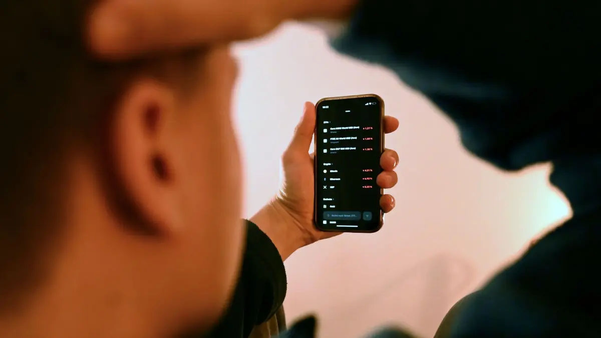 Trading mit Apps: ILLUSTRATION - 20.01.2026, Berlin: Ein junger Mann fasst sich an den Kopf, während er in der App eines Neobrokers auf seinem Smartphone Aktienkurse verfolgt. (zu dpa: «Neobroker boomen – haben junge Investoren das Finanzwissen?») Foto: Lilli Förter/dpa +++ dpa-Bildfunk +++