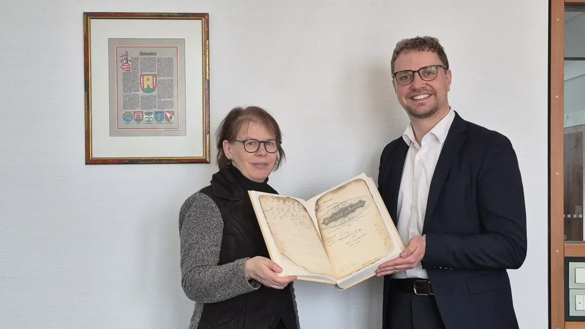 Kreisarchivarin Annette Bidlingmaier überreicht Hohensteins Bürgermeister Simon Baier die restaurierten Archivalienbände aus dem Gemeindearchiv Meidelstetten.