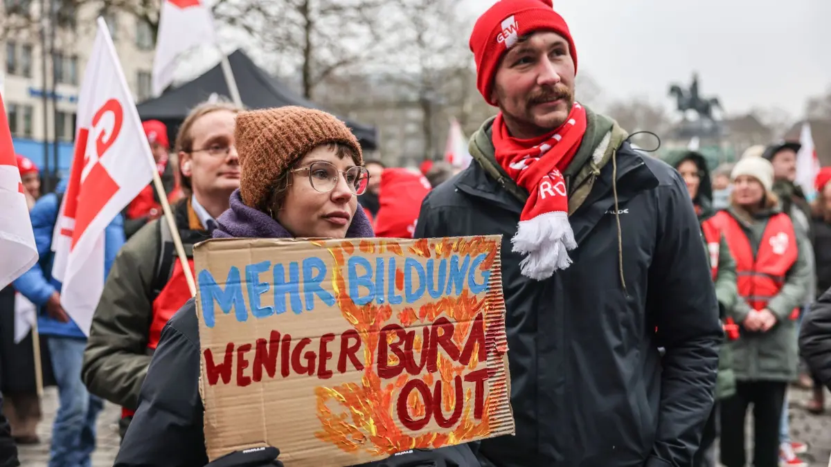 Bundesweiter „Streiktag Bildung“ - Köln: 29.01.2026, Nordrhein-Westfalen, Köln: Gewerkschafter halten auf einer Kundgebung in Köln ein Plakat mit der Aufschrift "Mehr Bildung - weniger Burnout" in der Hand. Die Gewerkschaft Erziehung und Wissenschaft (GEW) hat zu einem bundesweiten «Streiktag Bildung» aufgerufen. Foto: Oliver Berg/dpa +++ dpa-Bildfunk +++
