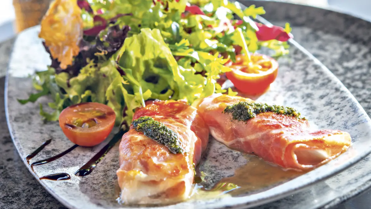 Büffelmozzarella in Parmaschinken an Salatspitzen.
