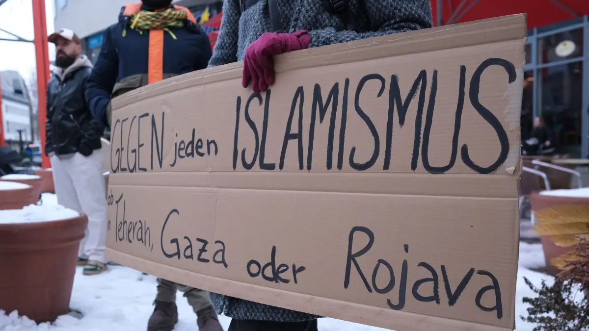Prokurdische Kundgebung in Jena: 31.01.2026, Thüringen, Jena: Eine Teilnehmerin einer prokurdischen Kundgebung trägt ein Schild mit der Aufschrift „Gegen jeden Islamismus…“. Mehrere hundert Menschen demonstrieren für die Rechte kurdischer Minderheiten im Norden Syriens. Foto: Sebastian Willnow/dpa +++ dpa-Bildfunk +++
