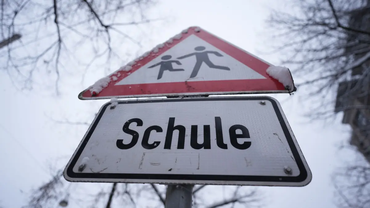 Winterwetter - Schulausfall in Hamburg: ARCHIV - 08.01.2026, Hamburg: Schnee liegt auf einem Verkehrsschild und Hinweisschild mit der Aufschrift „Schule“ vor einer Schule im Stadtteil St. Georg. Die Schulen in Hamburg bleiben wegen der Witterungsverhältnisse und des erwarteten starken Schneefalls am Freitag geschlossen. Das teilte die Schulbehörde mit. (zu dpa: «Warnstreik legt Nahverkehr vielerorts lahm - Was fährt noch?») Foto: Marcus Brandt/dpa +++ dpa-Bildfunk +++