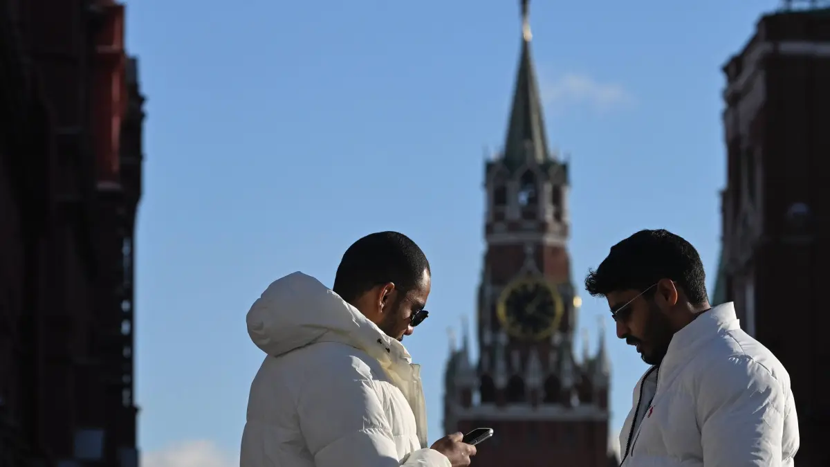 Russia Daily Life 9040455 05.11.2025 Tourists look at their smartphones at the entrance to the Red Square with the Kremlins Spasskaya tower seen in the background on a sunny autumn day in central Moscow, Russia. Maksim Blinov / Sputnik Moscow Russia PUBLICATIONxINxGERxSUIxAUTxESTxLTUxLATxNORxSWExDENxNEDxPOLxUKxAUSxONLY Copyright: Maksim Blinov