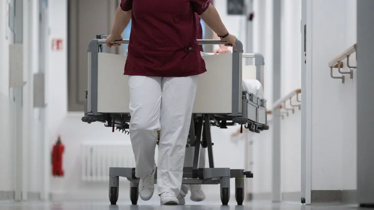 ARCHIV - 15.05.2024, Baden-Württemberg, Stuttgart: Eine Krankenpflegerin und ein Krankenpfleger schieben ein Krankenbett durch den Gang einer Station eines Krankenhauses. (zu dpa: «Steigt und steigt: Defizite der Kliniken an Milliardengrenze») Foto: Marijan Murat/dpa +++ dpa-Bildfunk +++