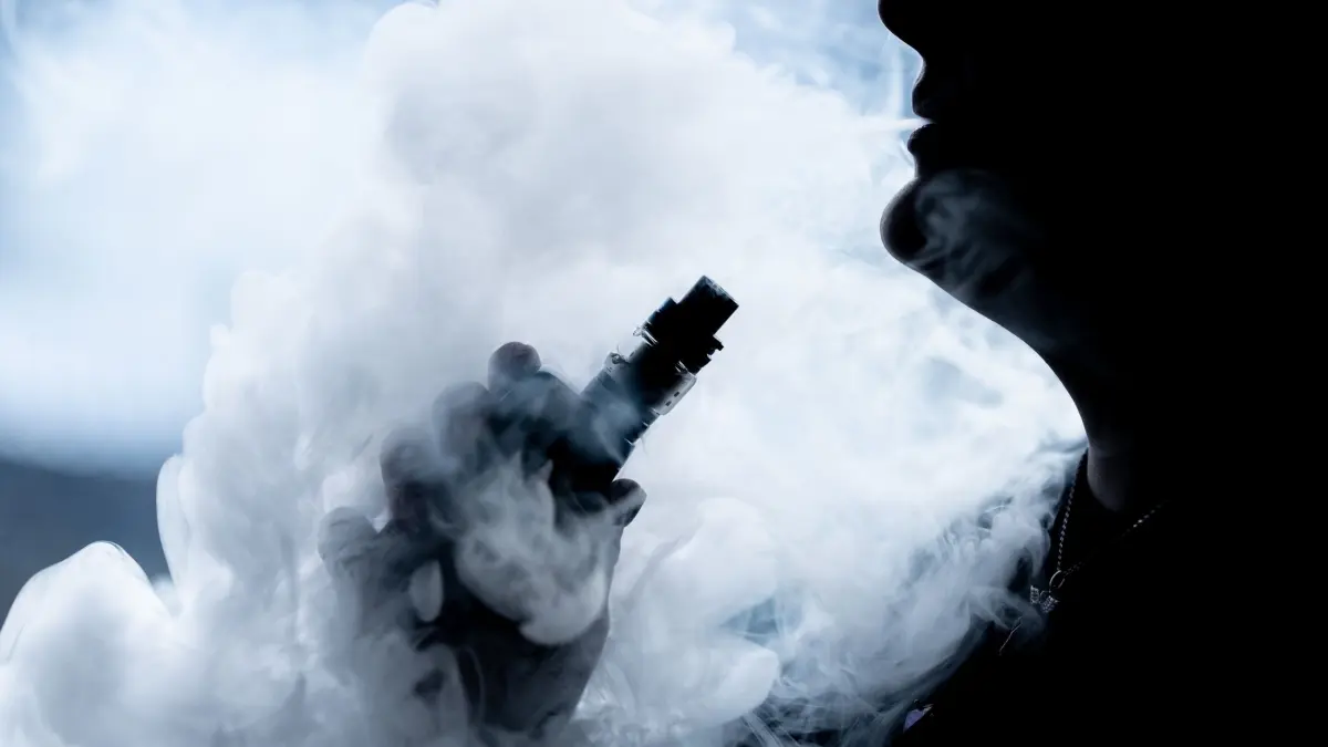 Illustration - Elektrische Shisha: ARCHIV - 07.02.2022, Baden-Württemberg, Bösingen: Eine junge Frau raucht in ihrer Wohnung mit einer E-Shisha und ist dabei als Silhouette zu sehen. (zu dpa: «Nach Notfällen - Polizei warnt vor «Baller-Liquids»») Foto: Silas Stein/dpa +++ dpa-Bildfunk +++