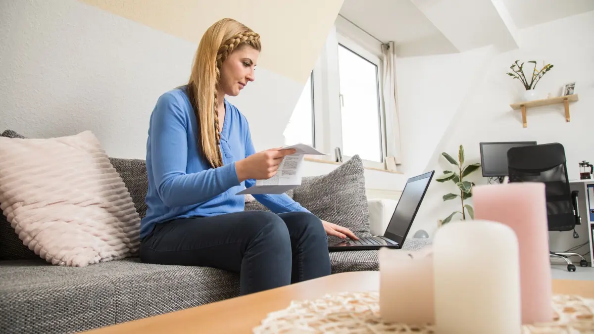 Frau sitzt mit einer Abrechnung vor einem Laptop
