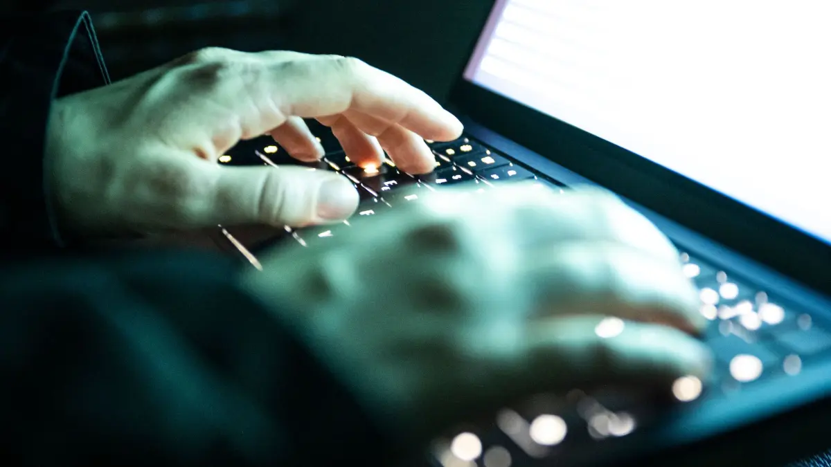 Cyberkriminalität: ILLUSTRATION - 14.12.2025, NA, Berlin: Eine Person tippt mit den Fingern auf einer beleuchteten Laptop-Tastatur. (gestellte Szene) (zu dpa: «Falsche Bankmitarbeiter bringen Mann um 10.000 Euro») Foto: Philip Dulian/dpa +++ dpa-Bildfunk +++