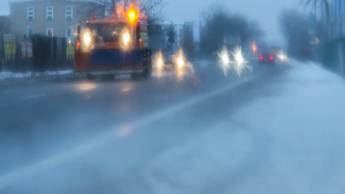 Winterwetter in Leipzig: 05.02.2026, Sachsen, Leipzig: Ein Fahrzeug des Winterdienstes fährt bei schlechten Sichtbedingungen über eine Straße in Leipzig (fotografiert durch die Windschutzscheibe eines Autos). Der Deutsche Wetterdienst warnt vor Glätte durch überfrierenden Regen. Foto: Jan Woitas/dpa +++ dpa-Bildfunk +++