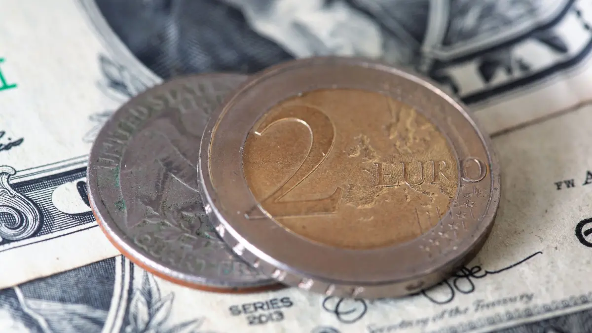 Euro und US-Dollar: SYMBOLBILD - 22.11.2024, Berlin: Eine Zwei-Euro-Münze liegt auf US-Dollar-Banknoten neben einer Quarter-Dollar-Münze. (zu dpa: «EZB hält Leitzinsen konstant») Foto: Fernando Gutierrez-Juarez/dpa +++ dpa-Bildfunk +++