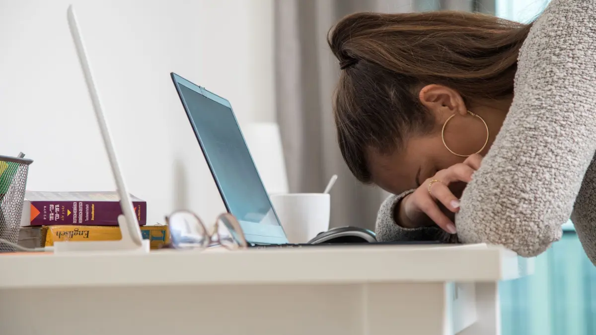 Eine junge Frau legt den Kopf auf den Tisch