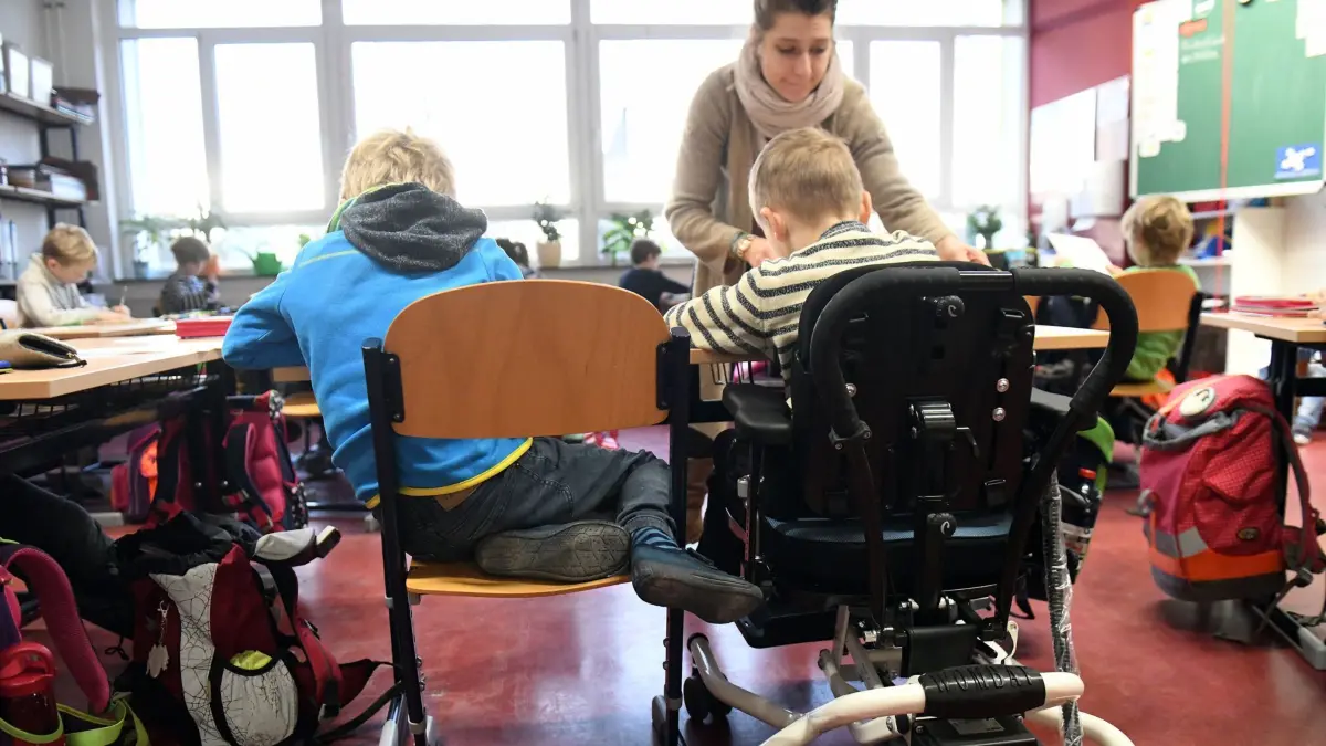 Ein Kind mit Behinderung sitzt am 07.12.2017 in der Rosa-Luxemburg-Grundschule in Potsdam (Brandenburg) in seinem Rollstuhl gemeinsam mit anderen Erstklässlern ohne Handicap in einem Klassenraum. Die Schule ist eine von 75 Grundschulen in Brandenburg, die bereits seit fünf Jahren Inklusion betreiben, die inzwischen Gemeinsames Lernen von Kindern mit und ohne Förderbedarf heißt. (zu dpa Serie Bildung in Brandenburg "Gemeinsames Lernen: Brande...