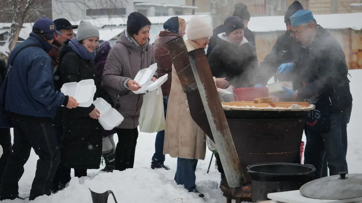 Ukraine-Krieg - Dnipro: 07.02.2026, Ukraine, Kiew: Der freiwillige Helfer Marat Darmenow (r) serviert den Einwohnern von Kiew während eines Stromausfalls, der durch die regelmäßigen russischen Luftangriffe auf das Energiesystem des Landes verursacht wurde, kostenlos warmes Essen. Foto: Sergei Grits/AP/dpa +++ dpa-Bildfunk +++