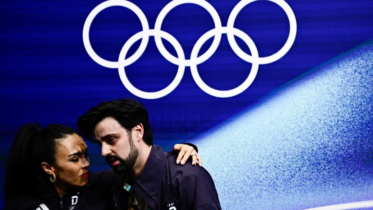 Germany's Jennifer Janse Van Rensburg and Germany's Benjamin Steffan react in the kiss and cry area after competing in the figure skating team event ice dance-rhythm dance during the Milano Cortina 2026 Winter Olympic Games at Milano Ice Skating Arena in Milan on February 9, 2026. (Photo by JULIEN DE ROSA / AFP)