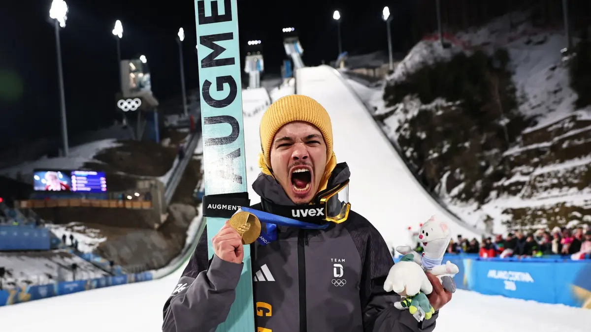 Olympische Winterspiele 2026: 09.02.2026, Italien, Predazzo: Olympia, Olympische Winterspiele Mailand Cortina 2026, Ski nordisch/Skispringen, Normalschanze, Männer, Durchgang 2, Olympiasieger Philipp Raimund (Deutschland) jubelt mit seiner Goldmedaille über den ersten Platz. Foto: Daniel Karmann/dpa +++ dpa-Bildfunk +++