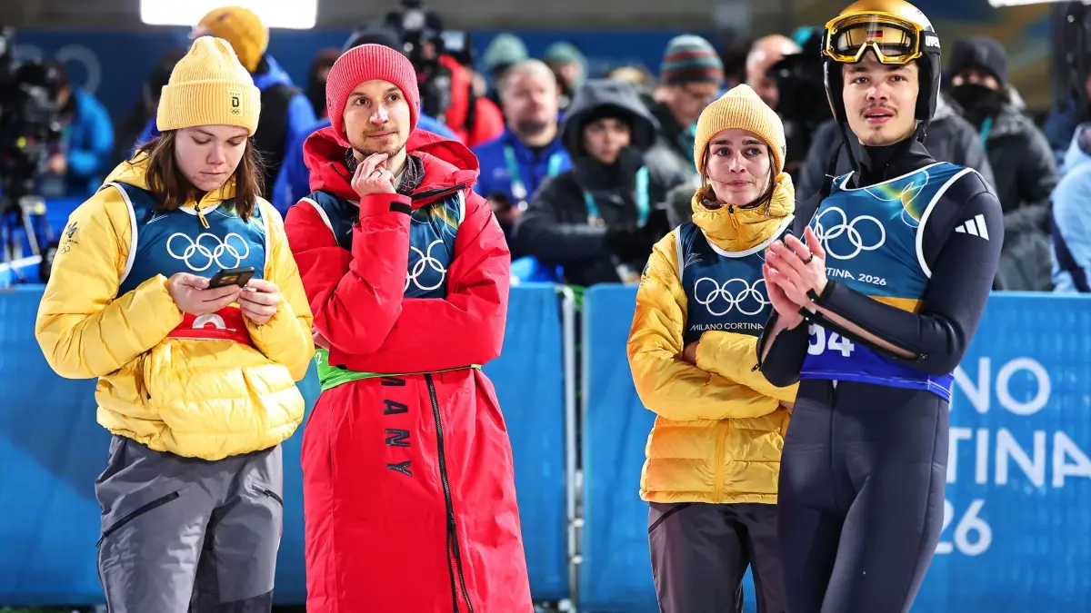 Olympische Winterspiele 2026: 10.02.2026, Italien, Predazzo: Olympia, Olympische Winterspiele Mailand Cortina 2026, Ski nordisch/Skispringen, Team, Mixed, Durchgang 2, Philipp Raimund (r, Deutschland) reagiert nach seinem Sprung neben den Teamkollegen Selina Freitag (2.v.r), Felix Hoffmann (2.v.l) und Agnes Reisch (alle Deutschland). (zu dpa: «Nach Gold-Sensation: Skisprung-Team knapp an Bronze vorbei») Foto: Daniel Karmann/dpa +++ dpa-Bildfunk +++