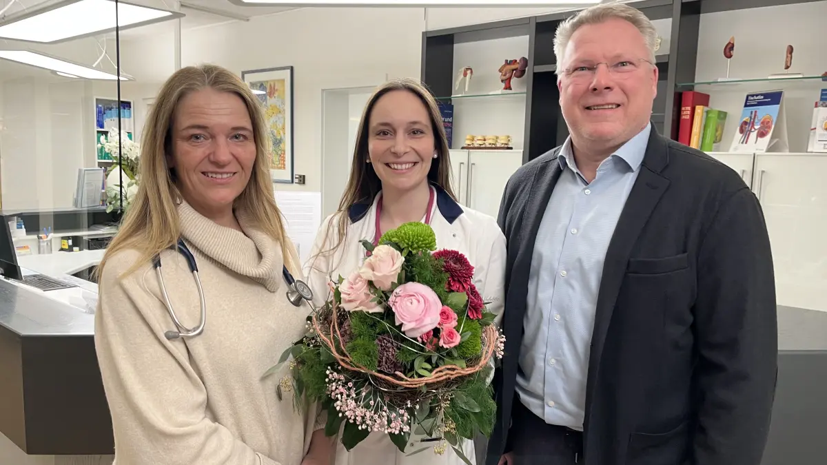Albpraxis Heroldstatt. Bürgermeister Michael Weber überreicht Dr. Julia Zimmermann einen Blumenstrauß. Die 29-jährige Internistin arbeitet seit Februar 2026 in der Albpraxis ihrer Mutter, Dr. Hannelore Zimmermann.