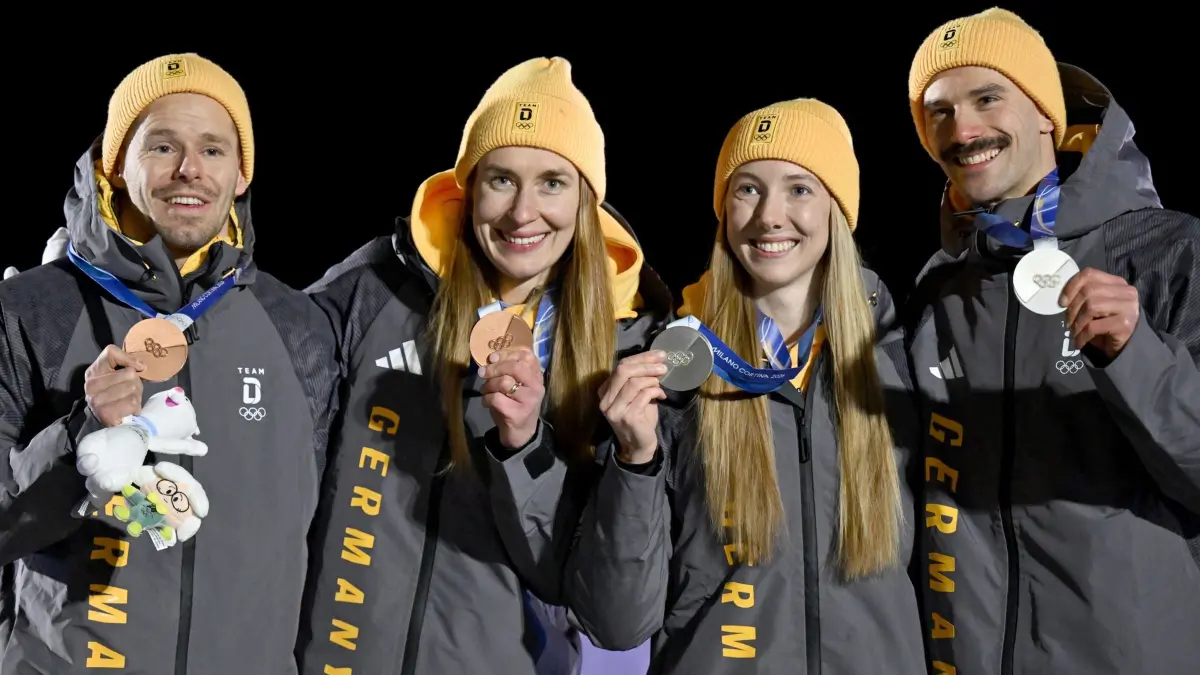 Olympische Winterspiele 2026: 15.02.2026, Italien, Cortina Džampezzo: Olympia, Olympische Winterspiele Mailand Cortina 2026, Skeleton, Team, Mixed im Cortina Sliding Centre, Susanne Kreher (Deutschland, 2.v.r.) und Axel Jungk (Deutschland, r) zeigen bei der Siegerehrung ihre Silbermedaillen neben Jacqueline Pfeifer (Deutschland, 2.v.l.) und Christopher Grotheer (Deutschland) mit der Bronzemedaille. Foto: Robert Michael/dpa +++ dpa-Bildfunk +++