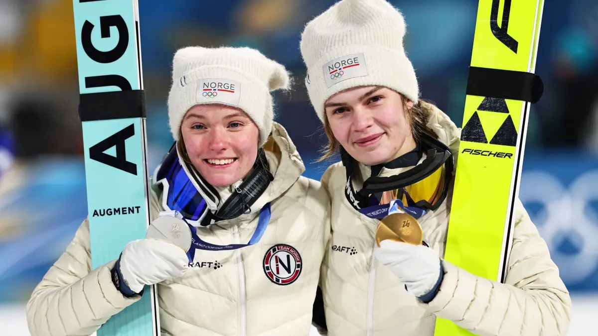 Olympische Winterspiele 2026: 15.02.2026, Italien, Predazzo: Olympia, Olympische Winterspiele Mailand Cortina 2026, Ski nordisch/Skispringen, Großschanze, Frauen, die Olympiasiegerin Anna Odine Strøm (r, Norwegen) und die Zweitplatzierte Eirin Maria Kvandal (Norwegen) jubeln bei der Siegerehrung über ihre Medaillen. Foto: Daniel Karmann/dpa +++ dpa-Bildfunk +++