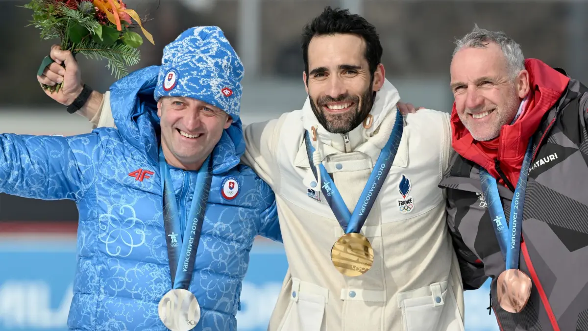 Olympische Winterspiele 2026: 15.02.2026, Italien, Antholz: Olympia, Olympische Winterspiele Mailand Cortina 2026, Biathlon, Anterselva Biathlon Arena, Martin Fourcade (Frankreich, M, Gold), Pavol Hurajt (Slowakei, l, Silber) und Christoph Sumann (Österreich, Bronze) freuen sich mit den Medaillen, die ihnen nachträglich für den 15 Kilometer Massenstart der Männer im Biathlon bei den Olympischen Winterspielen 2010 in Vancouver verliehen wurden. Foto: Hendrik Schmidt/dpa +++ dpa-Bildfunk +++