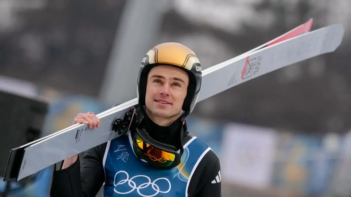 Olympische Winterspiele 2026: ARCHIV - 11.02.2026, Italien, Predazzo: Olympia, Olympische Winterspiele Mailand Cortina 2026, Ski nordisch/Kombination, Einzel, Männer, (Normalschanze/10 km), Vinzenz Geiger (Deutschland) geht während des Einzelwettbewerbs der Nordischen Kombination auf die Schanze. (zu dpa: «Wer gewinnt in letzter Olympia-Woche Gold für Deutschland?») Foto: Evgeniy Maloletka/AP/dpa +++ dpa-Bildfunk +++