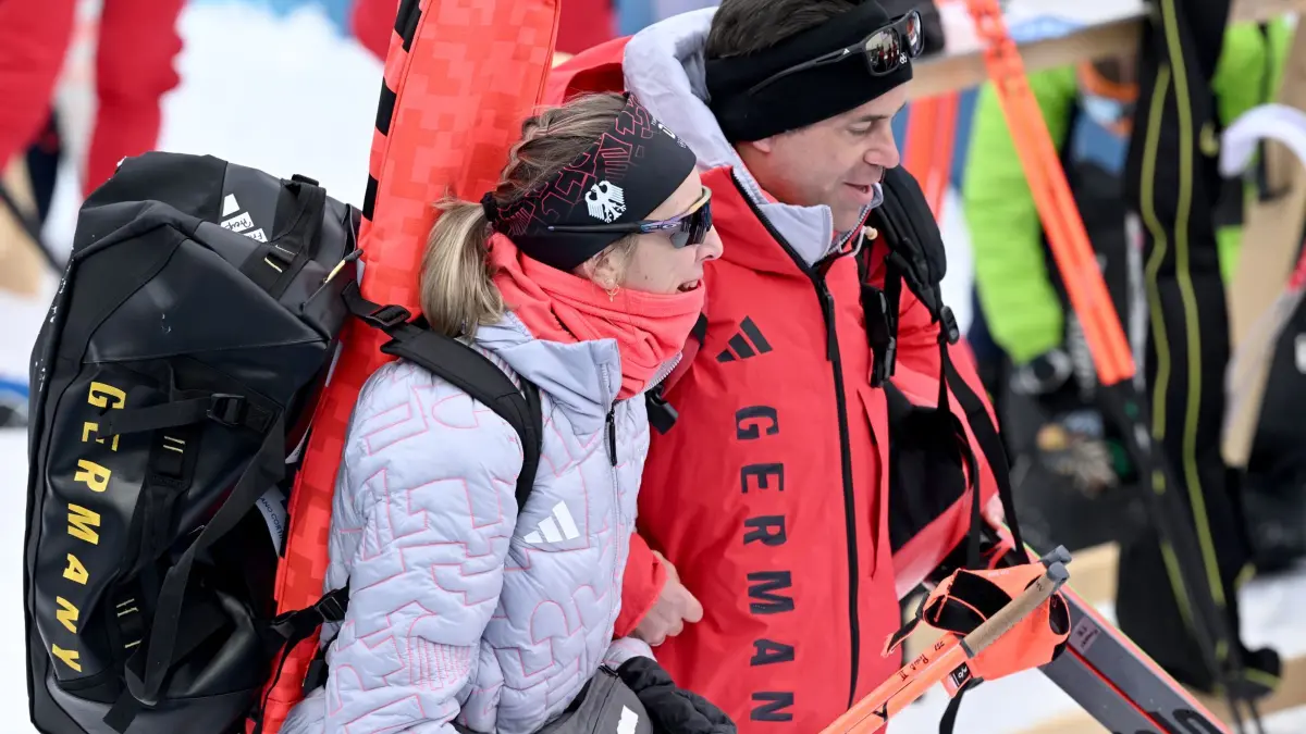Olympische Winterspiele 2026: 18.02.2026, Italien, Antholz: Olympia, Olympische Winterspiele Mailand Cortina 2026, Biathlon, Frauen, Staffel 4 x 6 Kilometer, Anterselva Biathlon Arena, Franziska Preuss aus Deutschland verlässt den Zielbereich mit Sebastian Torka, Teamarzt der deutschen Biathleten. Foto: Hendrik Schmidt/dpa +++ dpa-Bildfunk +++